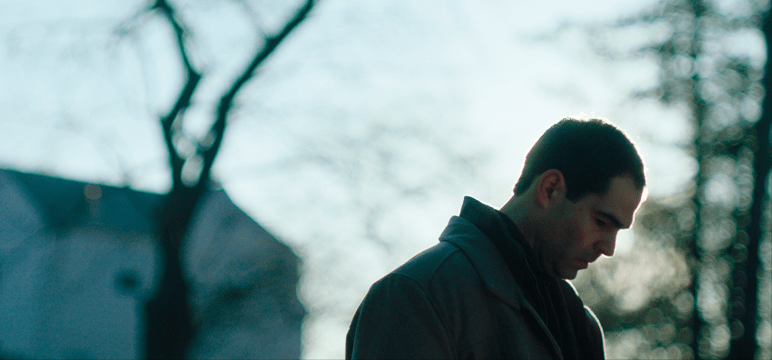 Image of a man looking down with the sun behind him