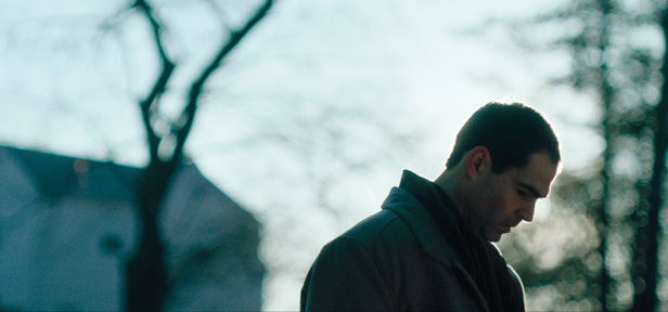 Image of a man looking down with the sun behind him