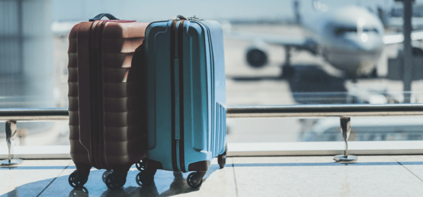 Image of the lower half of a person pulling luggage in an airport-type setting
