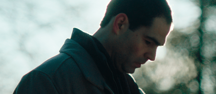 Image of a man looking down with the sun behind him