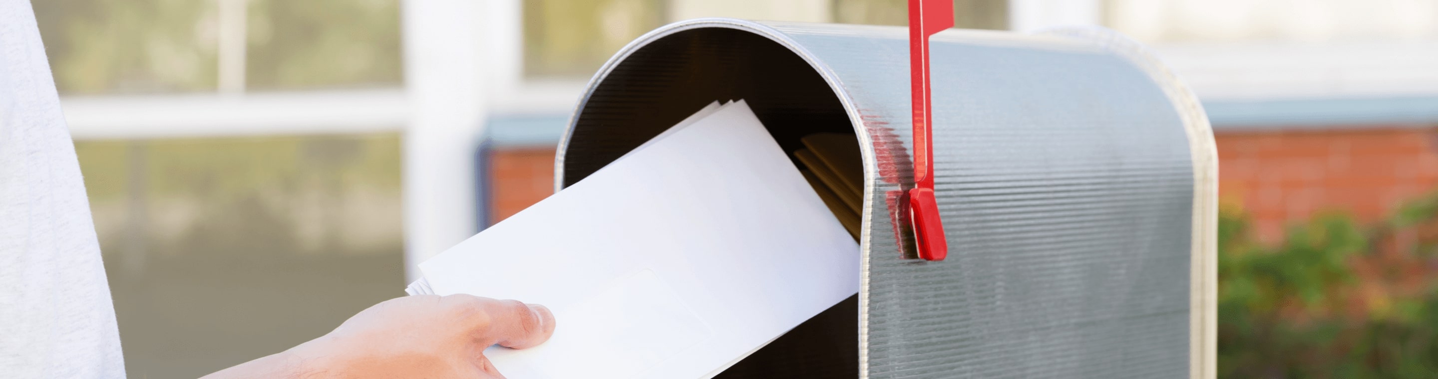 Hand putting letter into a mailbox