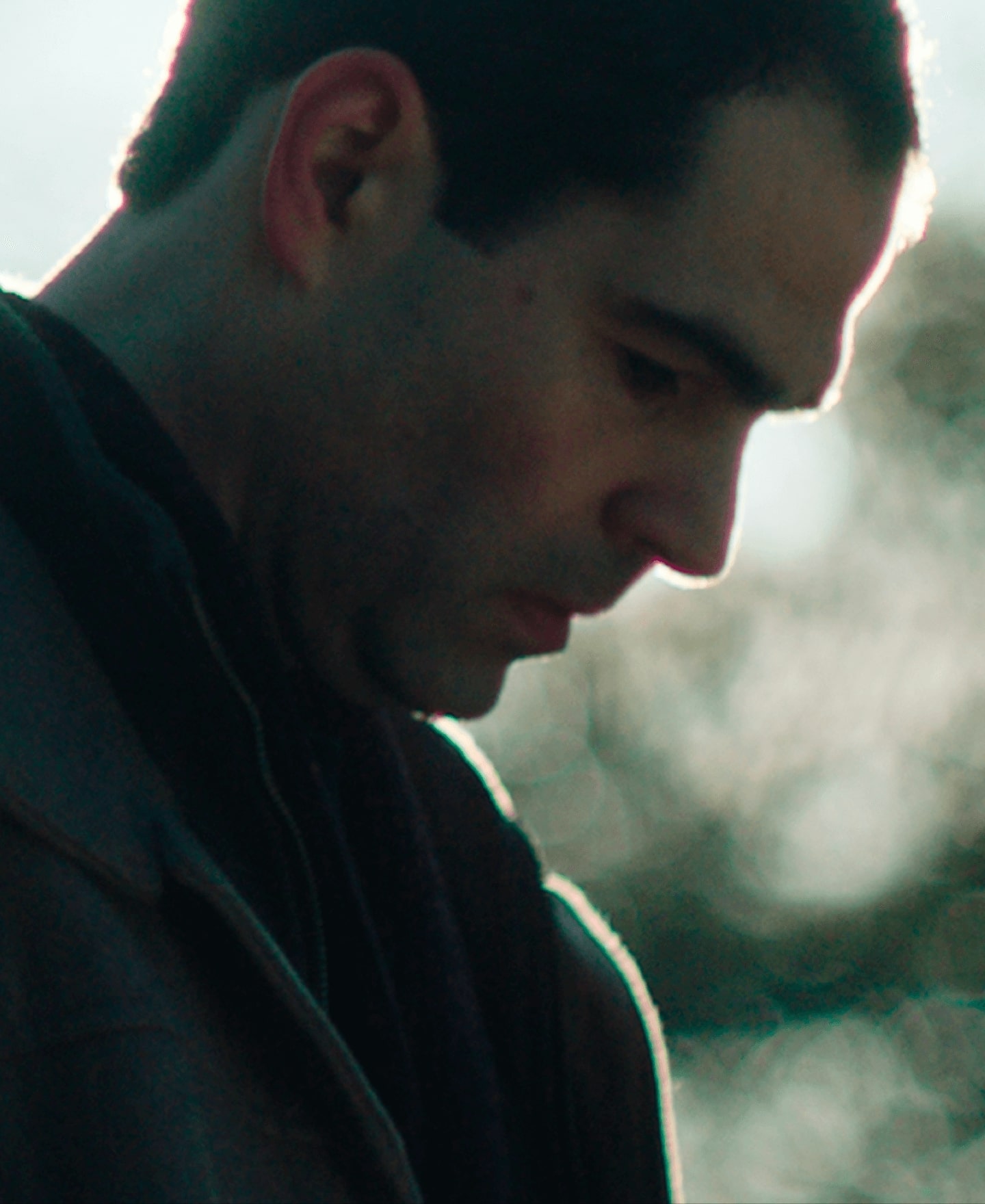 Image of a man looking down with the sun behind him