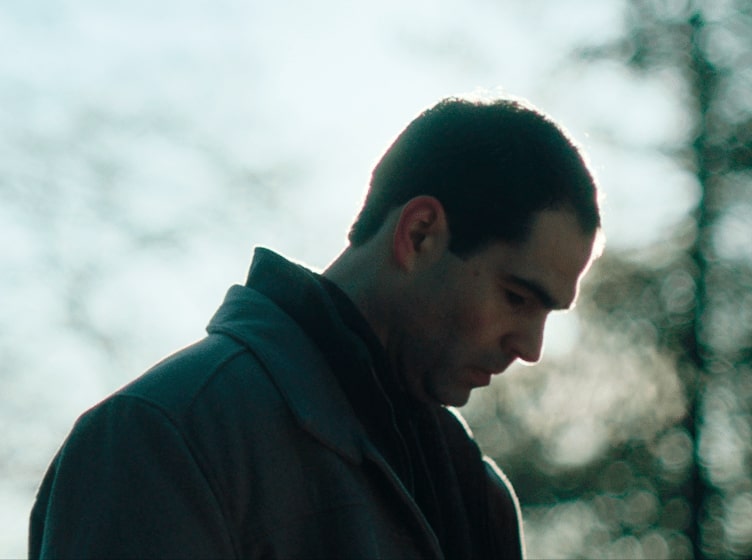 Image of a man looking down with the sun behind him