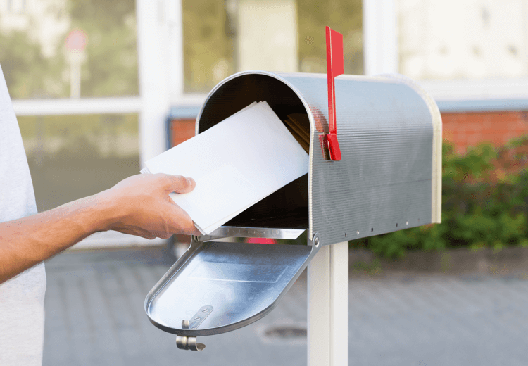Hand putting letter into a mailbox