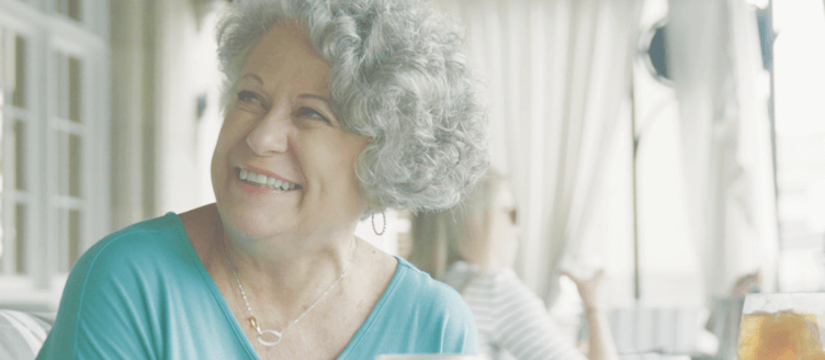 Image of a happy woman sitting at a table eating a meal