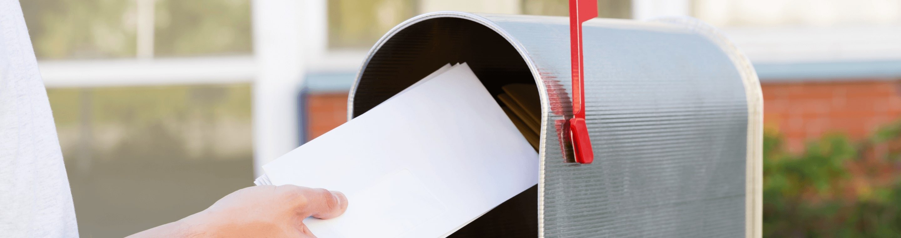 Hand putting letter into a mailbox