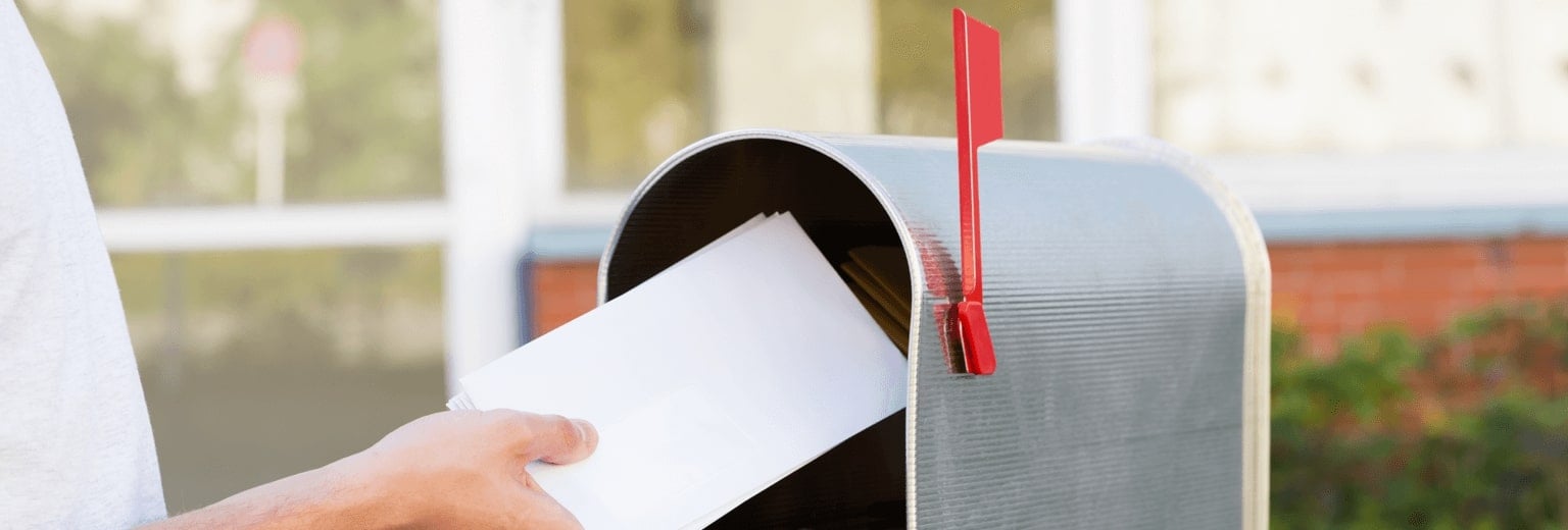 Hand putting letter into a mailbox