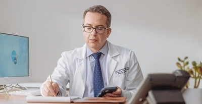 Male doctor writing notes at desk